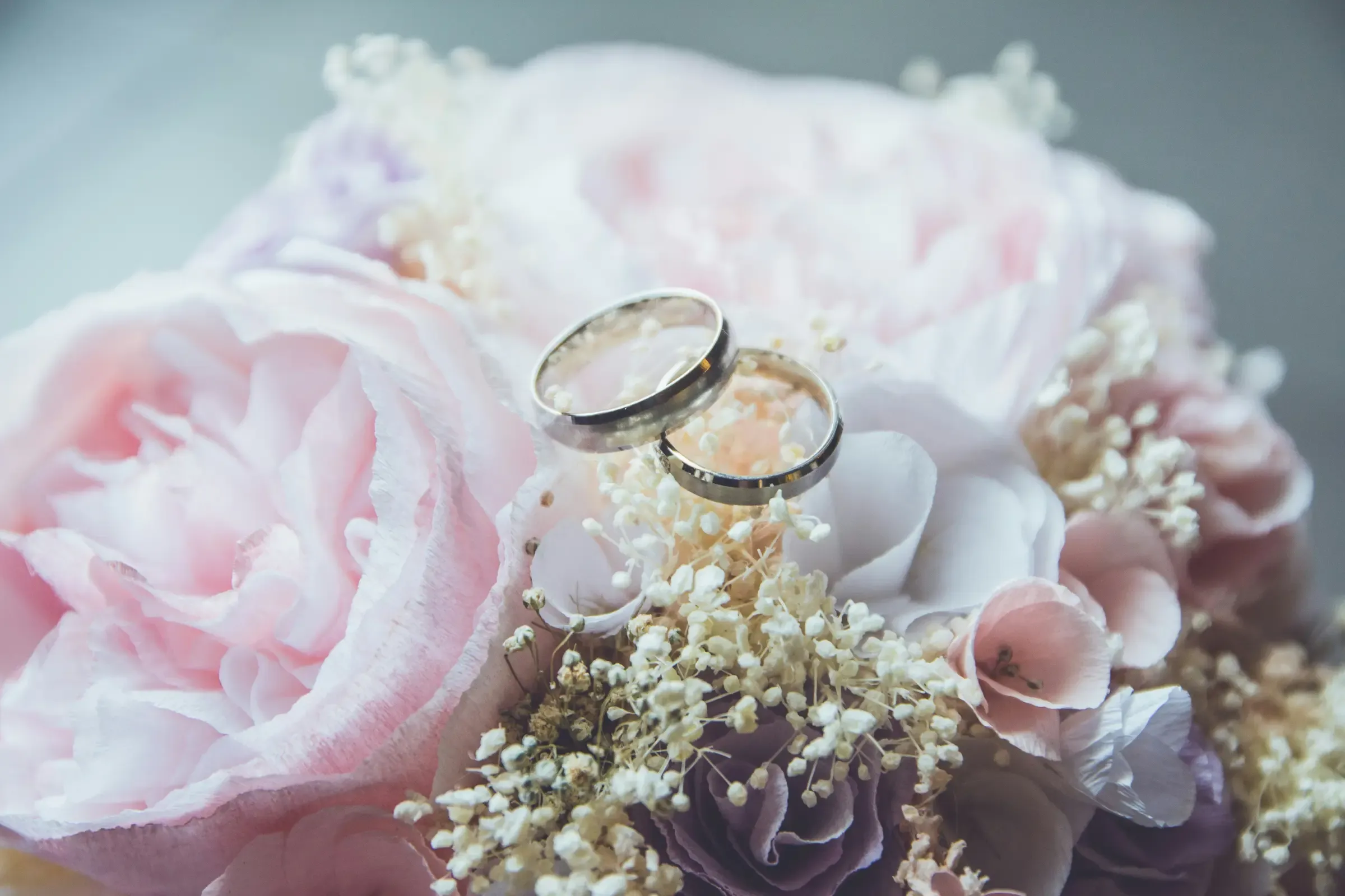 Deux alliances posées sur un bouquet de pivoines roses