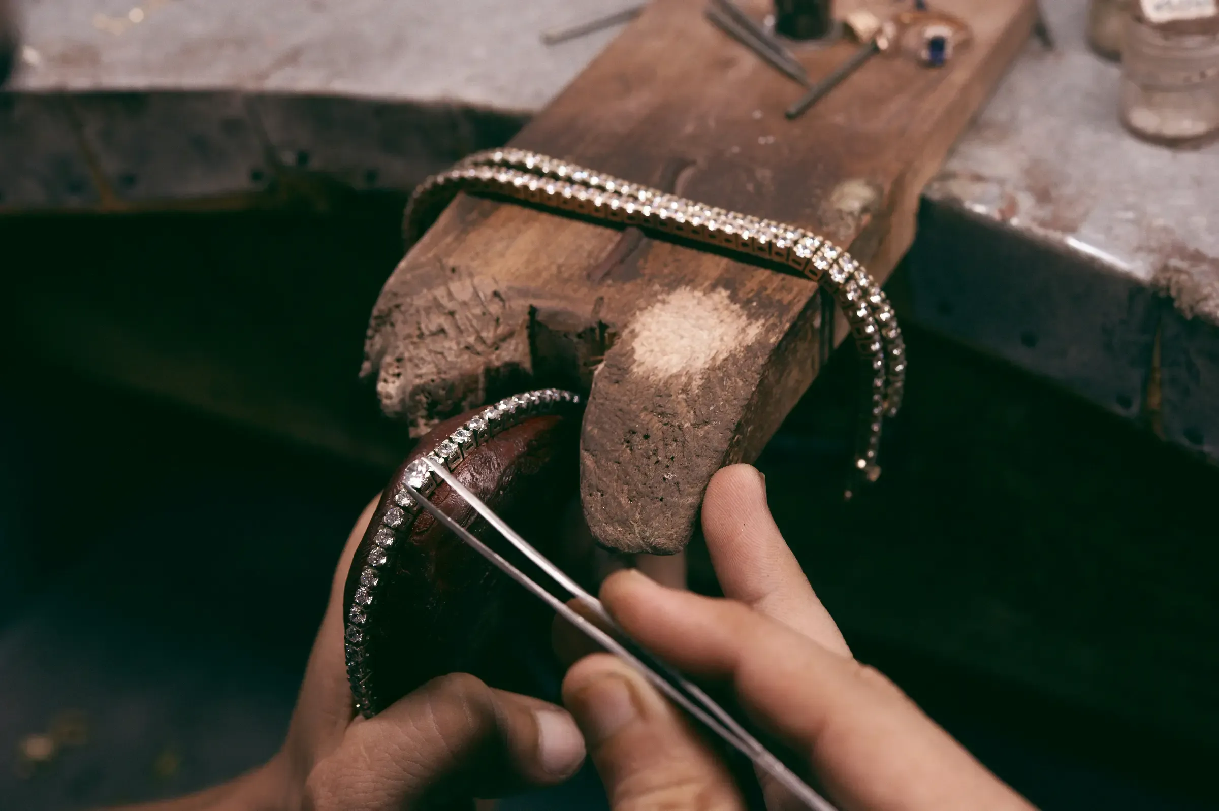 Bijoutier travaillant un bracelet rivière de diamants contre la cheville de l'établi