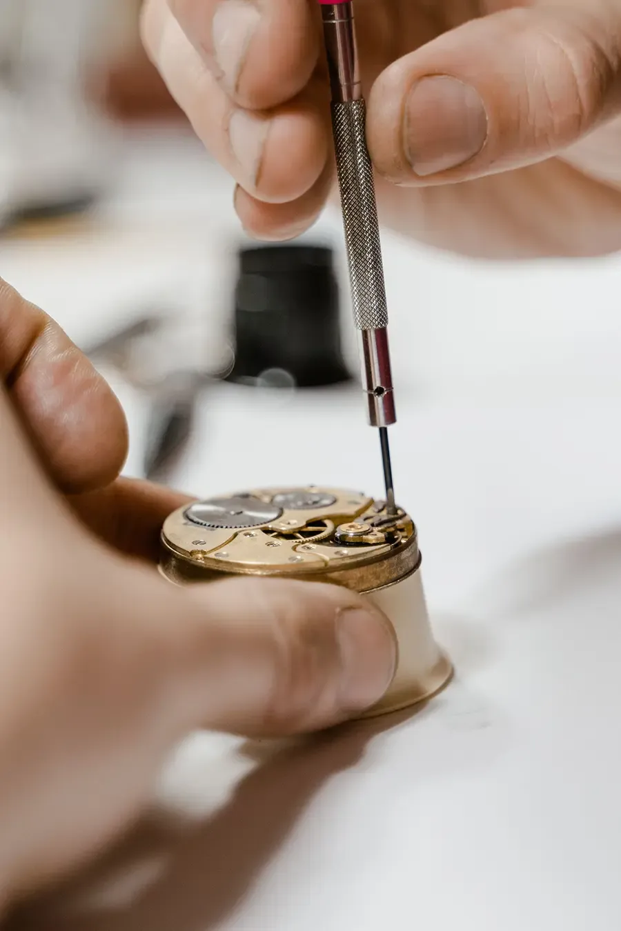 Horloger réparant un mouvement de montre à l'établi